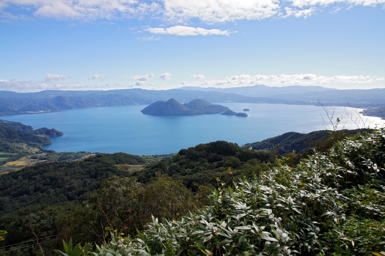 Lake Toya and its wooded islands beneath a blue sky